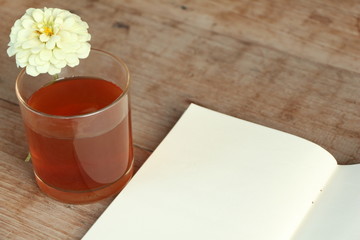 Hot tea, flower and blank note page.on wood table.