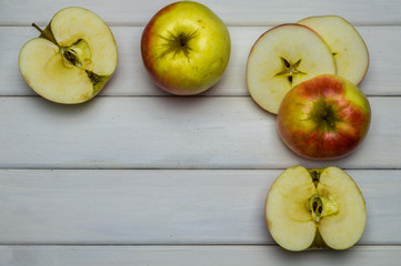 Whole and cut red and green ripe apples autumn harvest, from above on white wooden table
