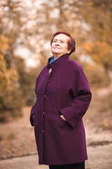 Senior woman 70-75 year old wearing winter jacket outdoors. Looking away.
