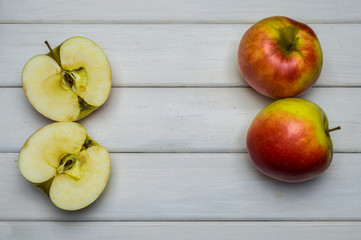 Whole and cut red and green ripe apples autumn harvest, from above on white wooden table