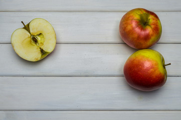 Whole and cut red and green ripe apples autumn harvest, from above on white wooden table