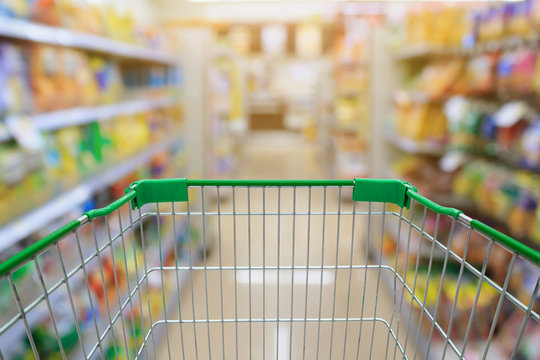Shopping cart in Supermarket Aisle and Shelves in blur backgroun