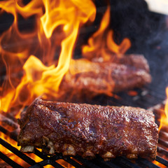 bbq pork ribs cooking on flaming grill