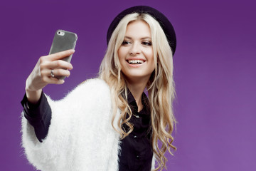 Fashion young girl taking picture of herself, selfie. Purple background