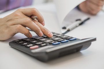Photo of hands holding pencil and pressing calculator buttons 