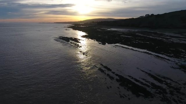 Aerial view over the ocean at sunrise.