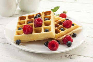 Handmade Belgian Waffles with raspberries  and blueberries on coffee table