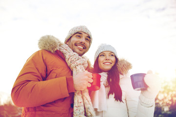 happy couple with tea cups over winter landscape