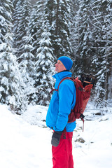 Fototapeta na wymiar Hiker with backpack standing among snow covered pine