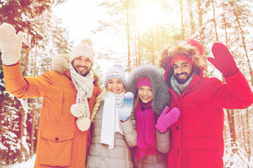 group of friends waving hands in winter forest