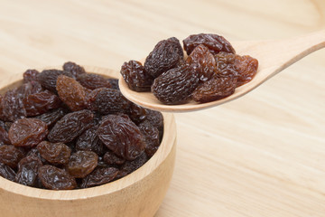 raisins in spoon with raisins in bowl.