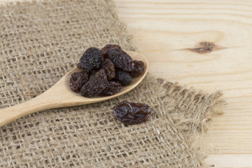 raisins in spoon on wooden table.