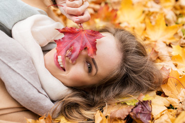 Obraz premium beautiful happy woman lying on autumn leaves