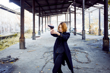 Woman pointing a gun. Mafia girl shooting at someone on the street.