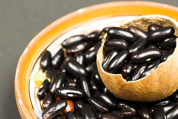 Black dried beans in a pumpkin shell and ceramics small plate with dark background