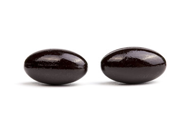 Two Black capsules in hand on a white background