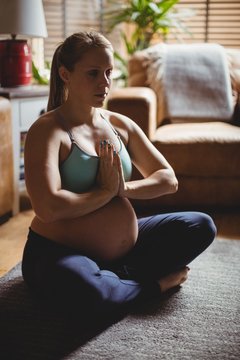Pregnant woman performing yoga in living room