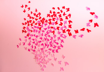 Paper pink rose and red butterflies in form of heart fly on a wall. Valentines day. 14 february
