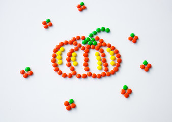 Symbol Halloween Holiday - a  yellow orange pumpkin made of small round candies. Isolated on a white background.