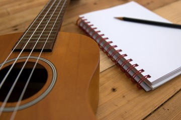 Ukulele guitar Notebook and pencil on wood table