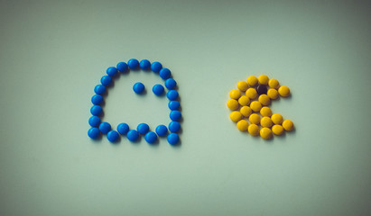 Color Candy pac man with ghost chasing it on white background arranged in pac-man style. Funny game with food,  closeup. Halloween holidays