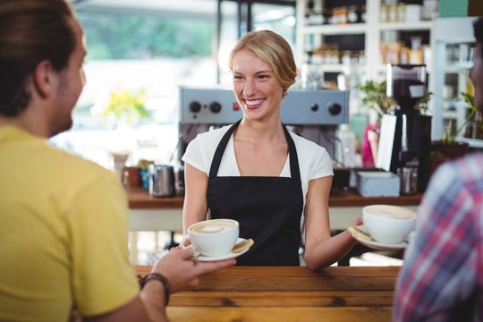 Smiling waitress serving cup of coffee to customer