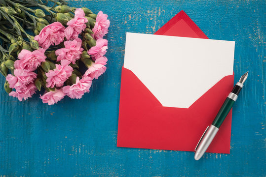 Carnations flowers, envelope and pen on a table
