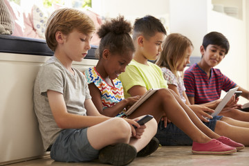 Group Of Children Sit On Floor And Use Technology