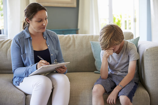 Young Boy With Problems Talking With Counselor At Home