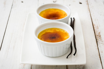 Traditional French creme brulee dessert with caramelized sugar on top, on wooden table


