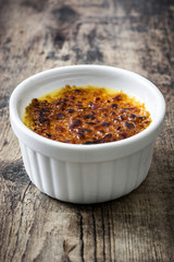 Traditional French creme brulee on rustic wooden table

