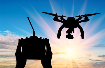 Silhouette flying drones and hands with remote control outdoors