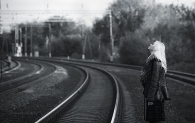 Beautiful young girl waiting for the train at the railroad track