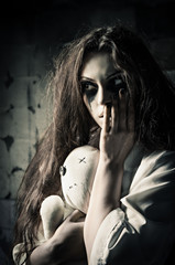 Horror style shot: strange sad girl with moppet doll in hands