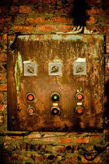 Old rusty control panel on the brick wall