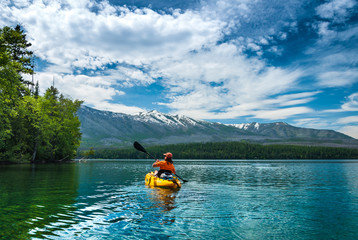 Kayaking in the spring by snow covered mountains on Lake McDonald in Glacier National Park Montana - 123664380