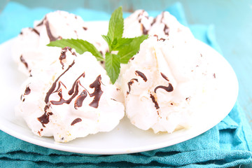 meringue cake with chocolate on a white plate on a blue background