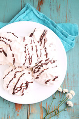 meringue cake with chocolate on a white plate on a blue background