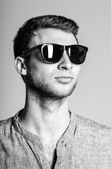 Portrait of handsome young man wearing sunglasses. Black and whi