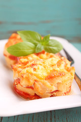 chicken baked with tomatoes and cheese on a white plate on a blue background