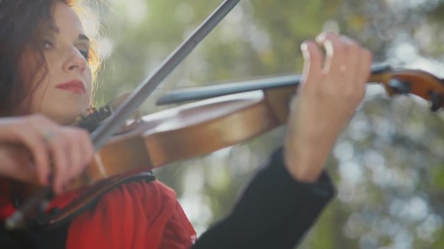 Close-up of fingers on the violin. Female hands of violinist. Girl violinist with a bright lipstick. Hands of a violinist. Violin, bow, string. Playing the violin in nature. Ease. Flight