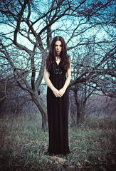 Portrait of beautiful goth girl amongst the faded trees
