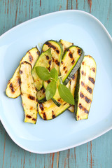 Zucchini grilled on a blue plate with basil