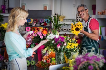 Smiling florist spraying water on flowers in flower shop