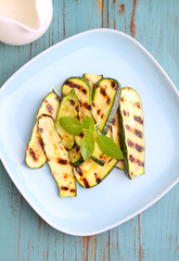 Zucchini grilled on a blue plate with basil