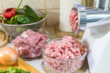 Home electric meat-grinder is making pork stuffing in a modern kitchen. Pork stuffing in a glass bowl.