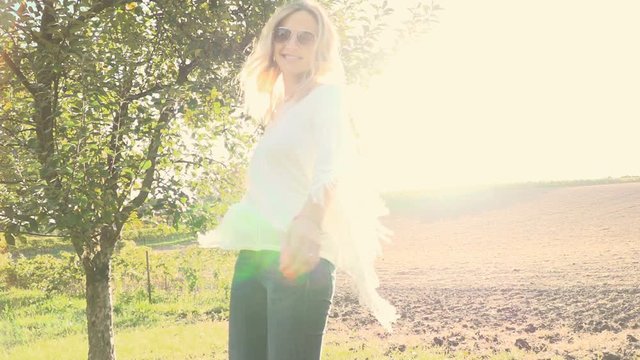 Frau am Morgen vor braunem Feld mit Sunflare