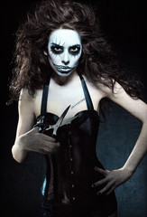 Young woman in the image of evil gothic freak clown with scissors. Grunge texture effect