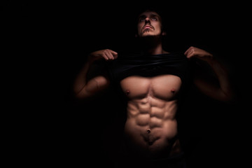 Naklejka na ściany i meble Muscular athlete man with a naked torso on a dark background