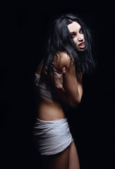 Fototapeta na wymiar Horror shot: portrait of angry evil young girl among dark